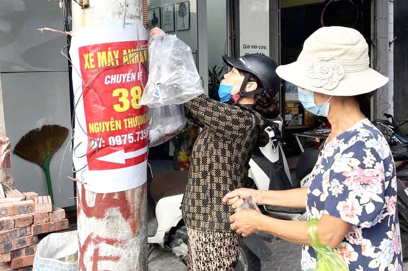 Người dân thành phố Hải Dương bóc gỡ quảng cáo trên cột điện.