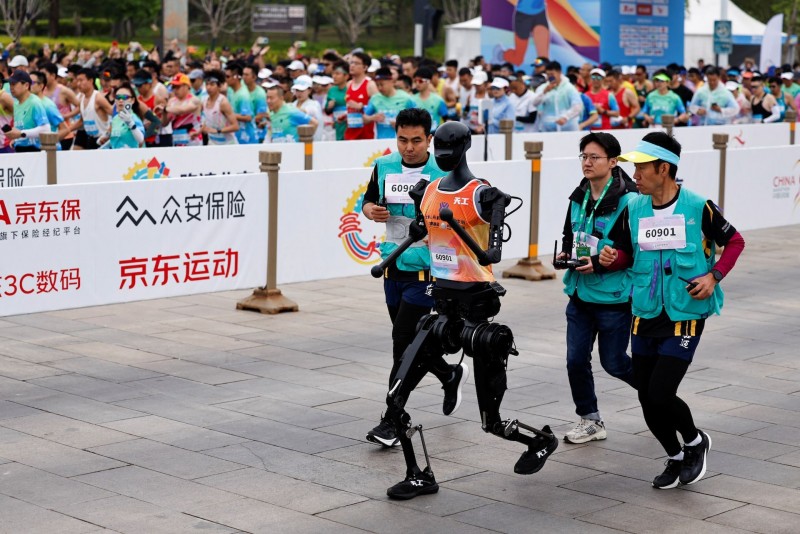 Đây là lần đầu tiên robot hình người chạy đua cùng con người trong cuộc thi bán marathon. Ảnh: Theo Reuters.