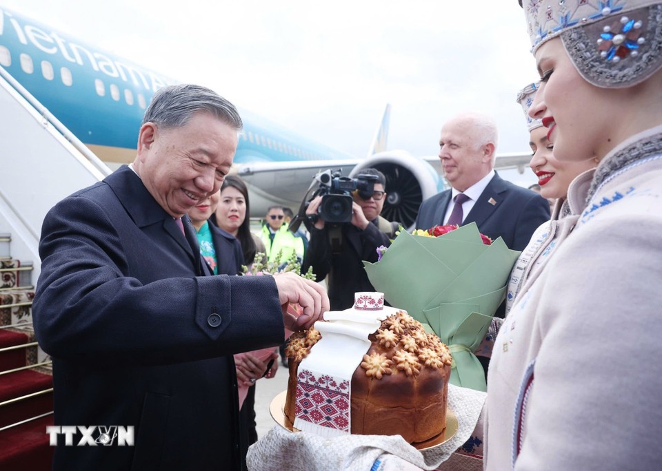 Thiếu nữ Belarus trong trang phục truyền thống trân trọng mời Tổng Bí thư Tô Lâm thưởng thức bánh mì và muối theo nghi thức đón khách quý của Belarus. Ảnh: TTXVN.