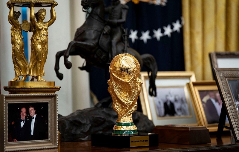Mô hình chiếc cúp vàng World Cup 2026 mà Chủ tịch FIFA Infantino tặng được Tổng thống Trump đặt trên chiếc bàn phía sau bàn làm việc. Ảnh: Bloomberg