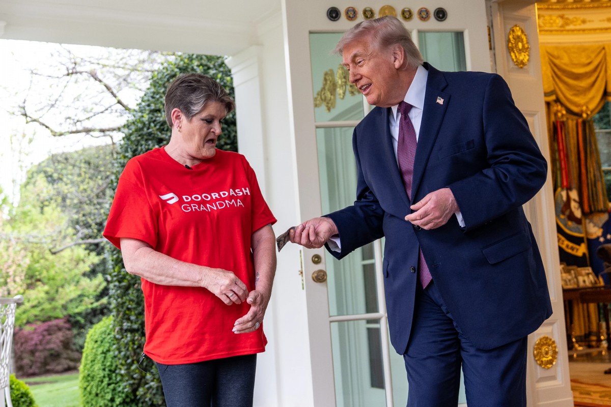 Tổng thống Donald Trump boa 100 USD cho bà Sharon Simmons tại Nhà Trắng ngày 13/4. Ảnh: AP