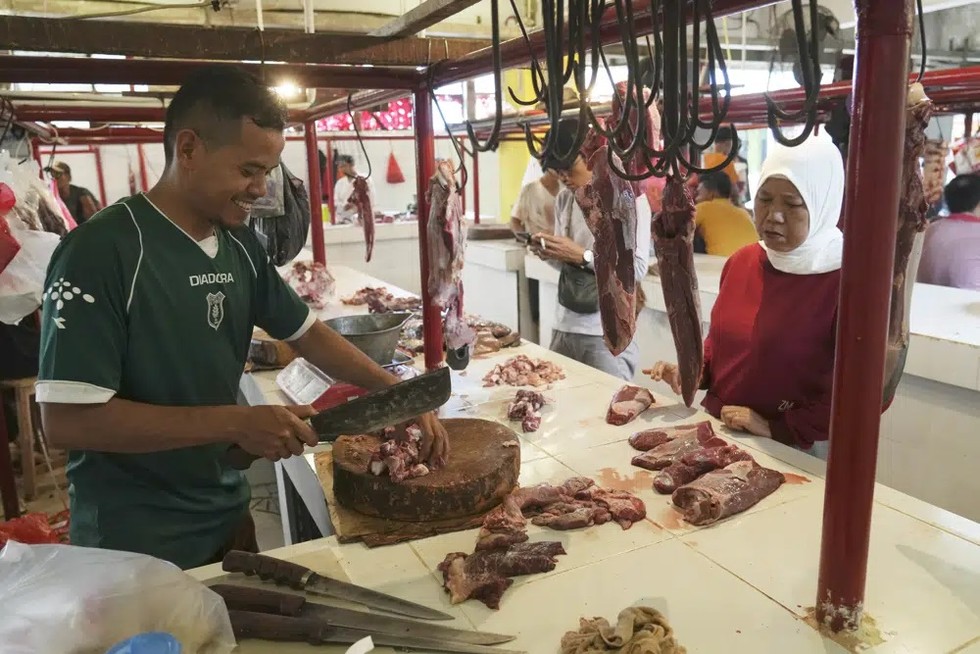 Một người b&aacute;n thịt v&agrave; kh&aacute;ch h&agrave;ng của m&igrave;nh tại một chợ ở Jakarta, Indonesia ng&agrave;y 22/3. Ảnh: AP