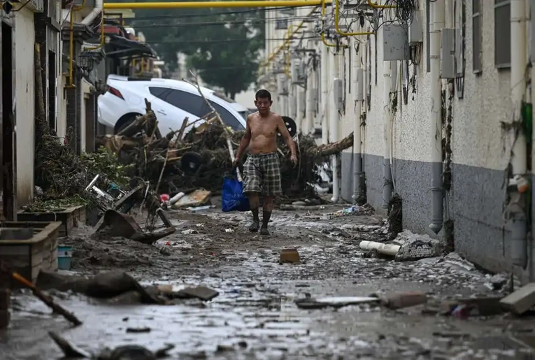 Một người d&acirc;n đi bộ tr&ecirc;n con đường lầy sau trận lũ lụt, Bắc Kinh, ng&agrave;y 3/8. Ảnh: AFP